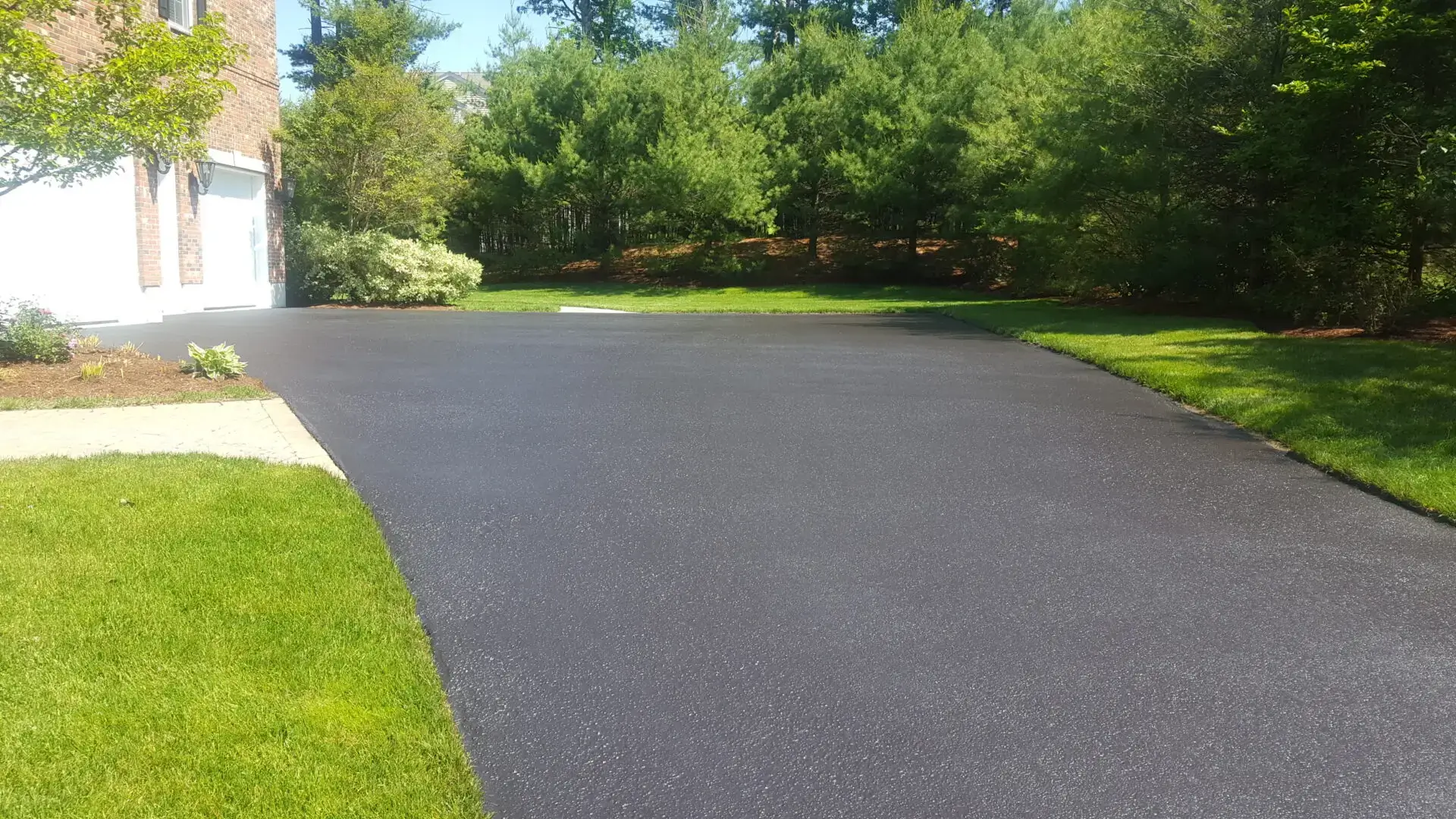 A driveway with grass and trees in the background.
