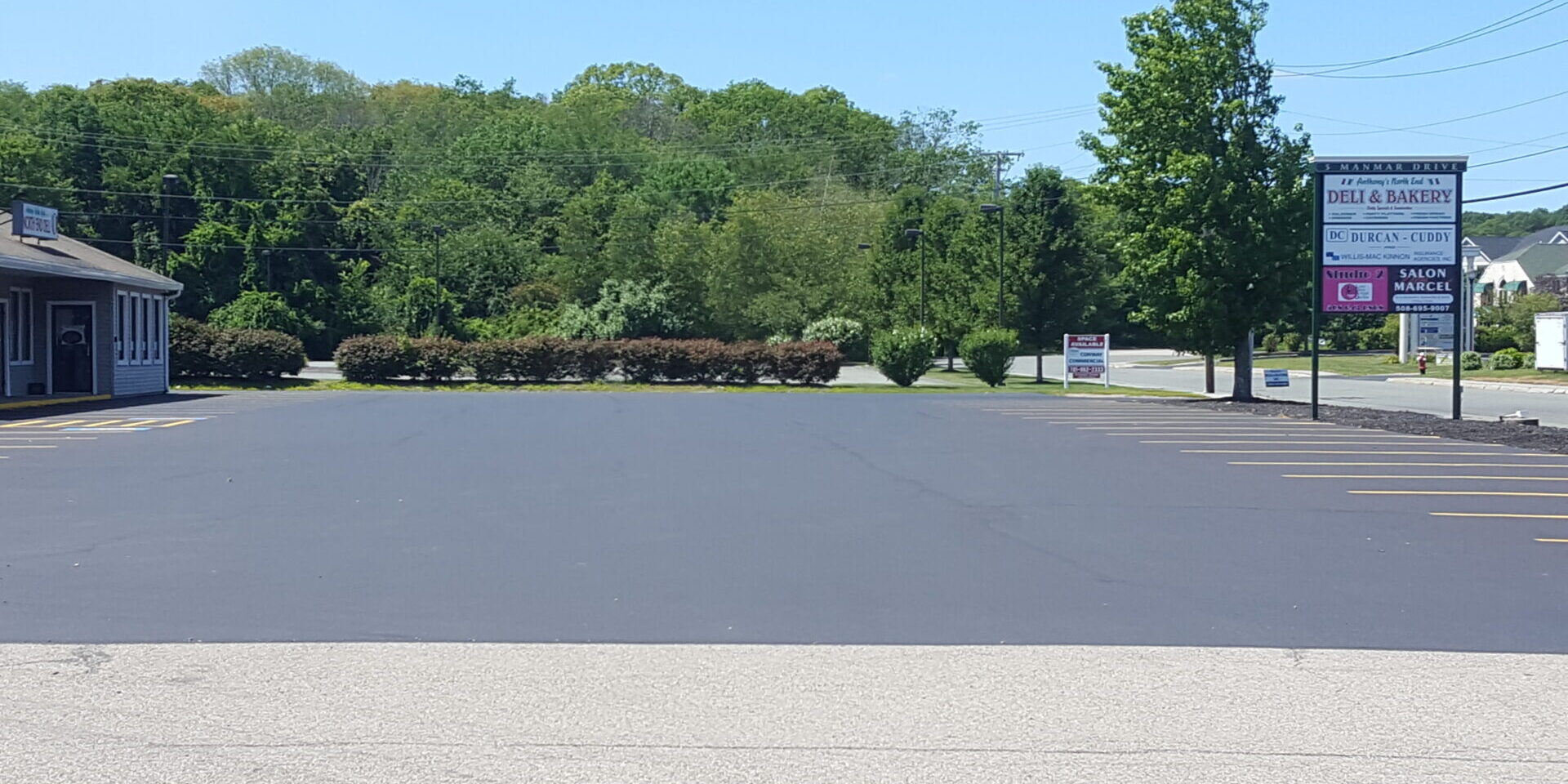 20170730_120936 A parking lot with trees and bushes in the background.